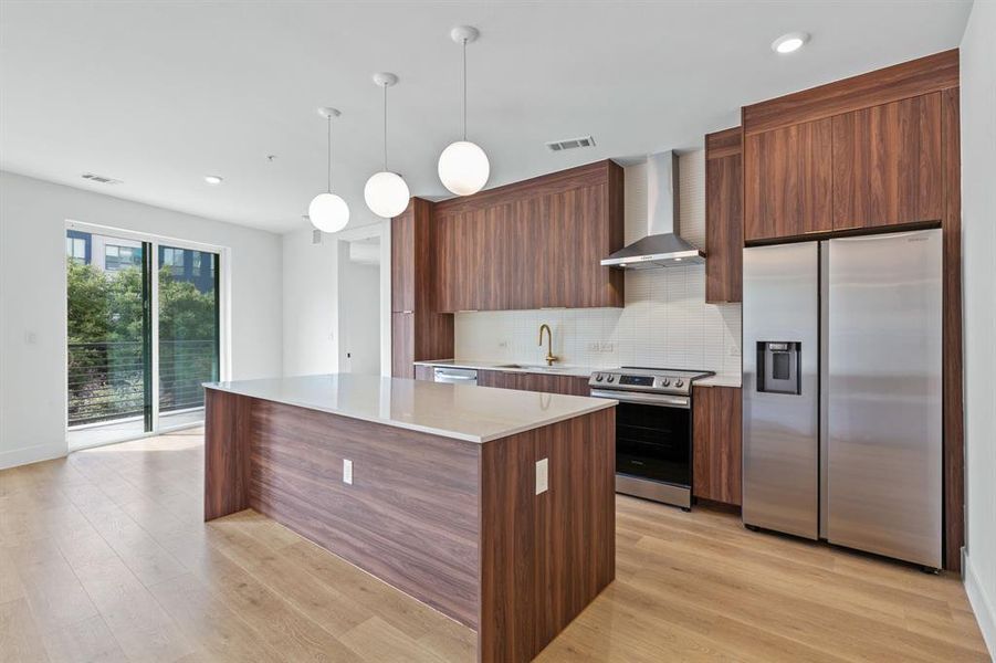 Unit 214 features the "Warm" finish scheme which includes rich walnut-colored cabinetry in the kitchen, black pulls and fixtures, Carrara marble-style quartz countertops, plus a full Samsung appliance package.