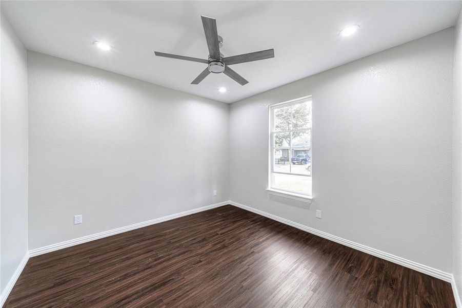 Empty room featuring dark wood-type flooring, ceiling fan, and recessed lighting