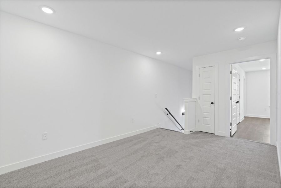 Carpeted floor, recessed lighting, white walls, white trim, and a white paneled door