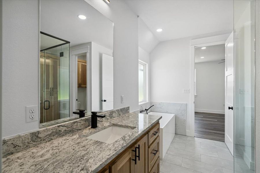 Bathroom with vanity, a bathtub, a stall shower, vaulted ceiling, and recessed lighting
