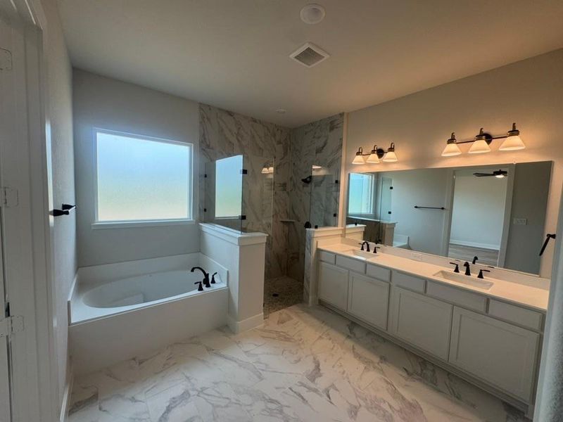Spacious bathroom featuring marble-look tile flooring, a built-in soaking tub with a frosted window, and a walk-in shower with glass enclosure Spacious bathroom featuring marble-look tile flooring, a built-in soaking tub with a frosted window, and a walk-in shower with glass enclosure