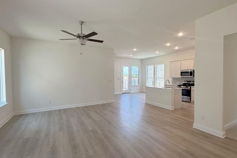 Open-concept living space featuring light wood-finish flooring, recessed lighting, and a ceiling fan