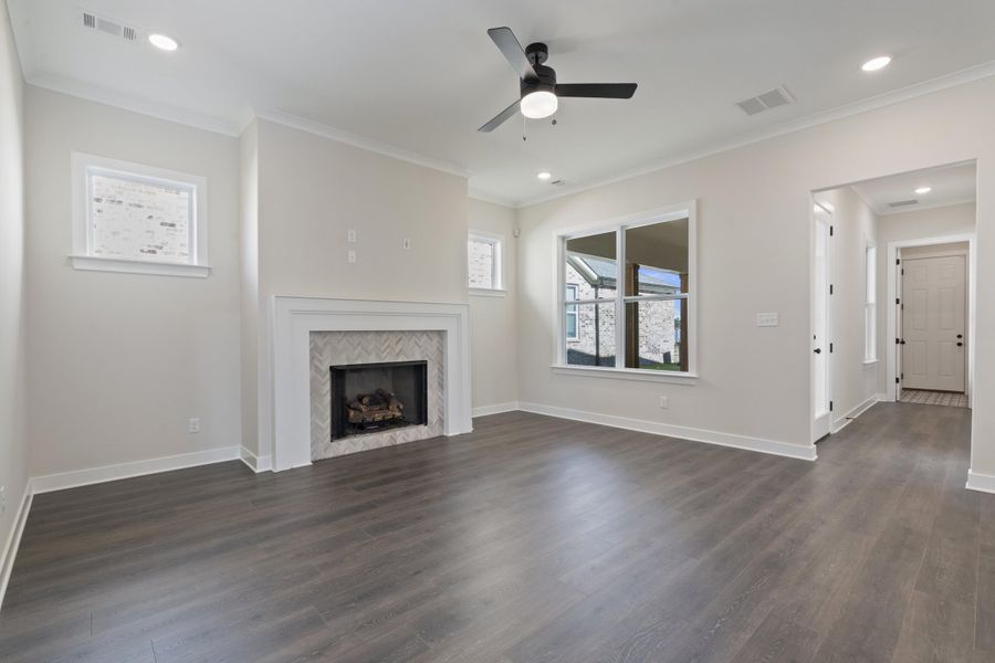 Unfurnished living room featuring dark wood-type flooring, recessed lighting, crown molding, ceiling fan, and a fireplace Unfurnished living room featuring dark wood-type flooring, recessed lighting, crown molding, ceiling fan, and a fireplace