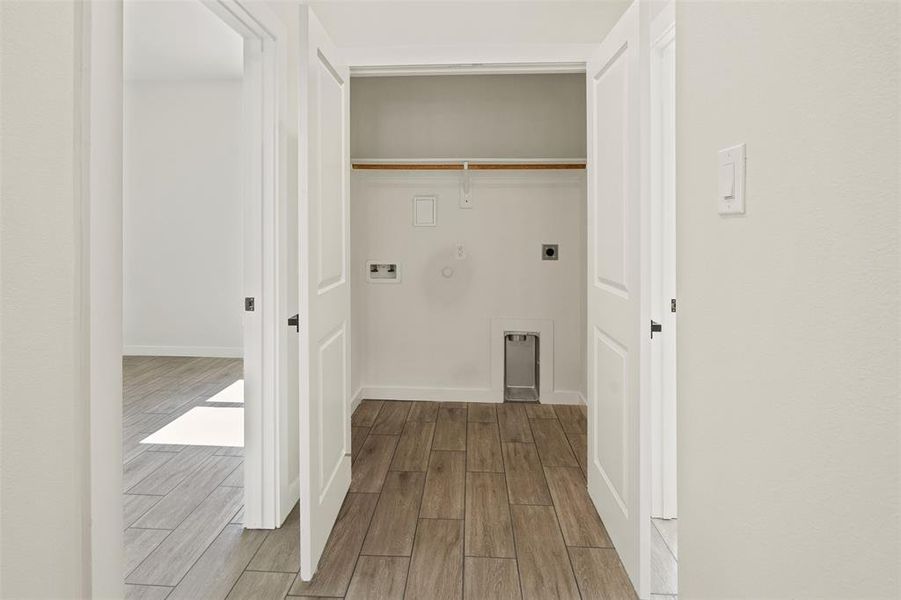 Dedicated laundry area featuring wood-finish flooring, white walls, and a clothing rod Dedicated laundry area featuring wood-finish flooring, white walls, and a clothing rod