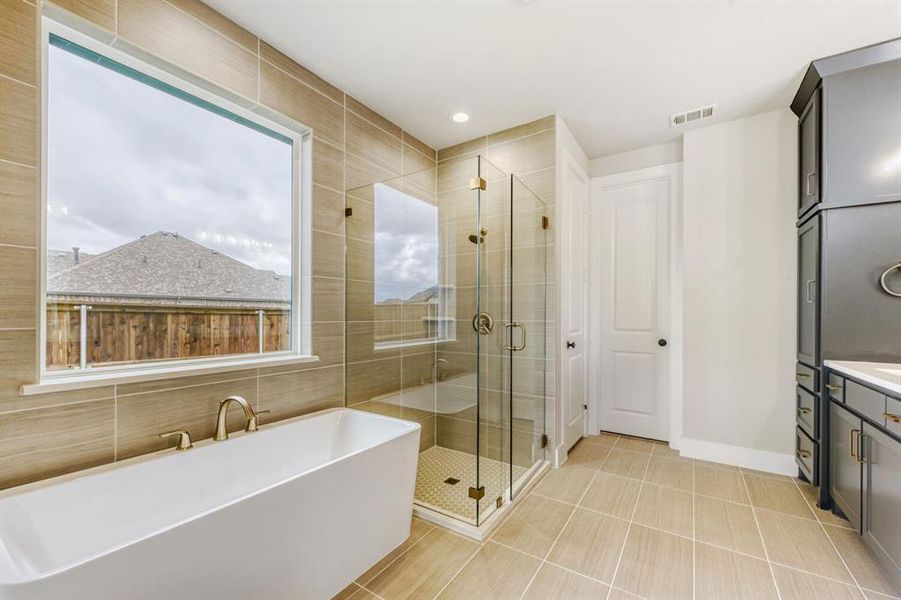 Bathroom with a freestanding tub, a shower stall, vanity, light tile patterned flooring, and recessed lighting