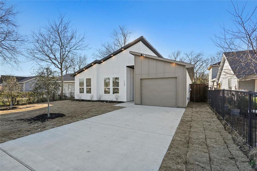 View of front of house with concrete driveway, an attached garage, and fence