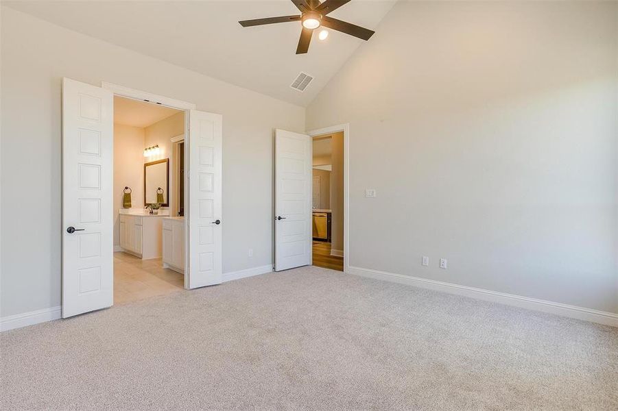 Unfurnished bedroom featuring light carpet, ceiling fan, and high vaulted ceiling