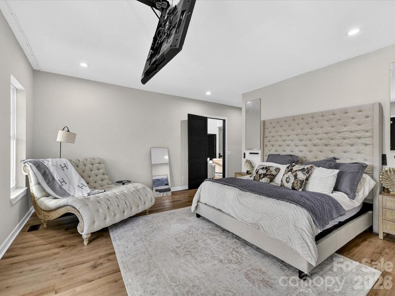 Spacious primary suite featuring elegant finishes, a cozy sitting area, and direct access to outdoor views through French doors.