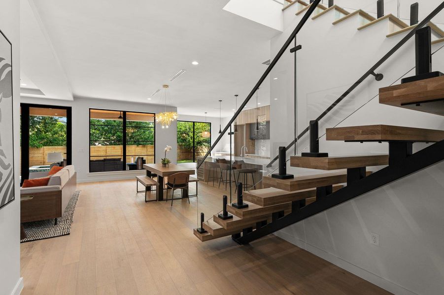 An open floorplan connects the dining area to a modern floating staircase.