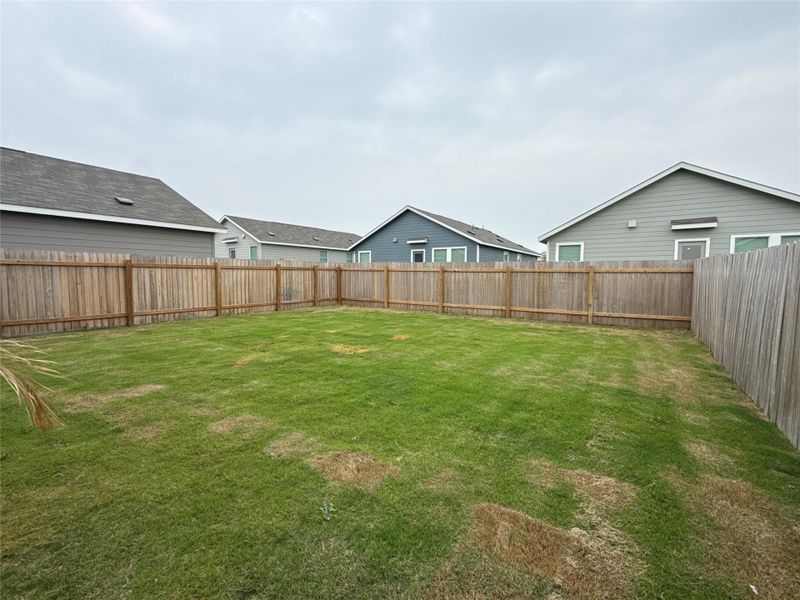 Expansive backyard featuring a natural wood privacy fence enclosing a generous grass lawn