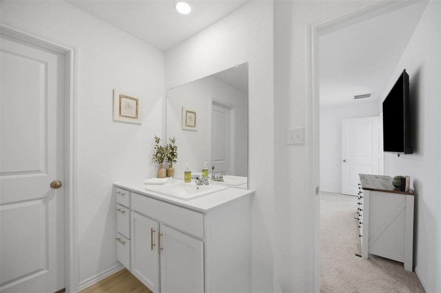 Recessed lighting illuminates a modern vanity with clean lines and adjacent bedroom views.