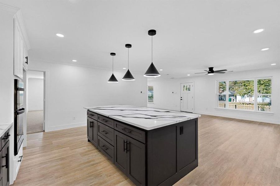 Kitchen featuring white cabinetry, decorative light fixtures, recessed lighting, light wood-style flooring, and a center island