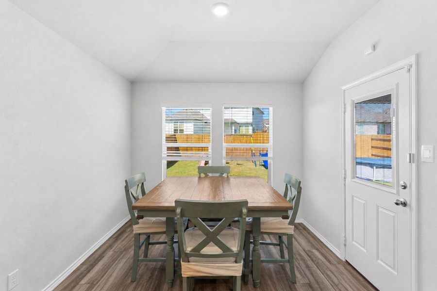Dining area bathed in natural light, featuring elegant wood flooring and direct yard access. Dining area bathed in natural light, featuring elegant wood flooring and direct yard access.