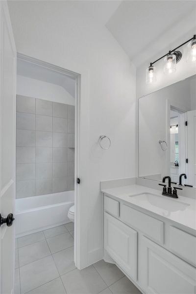 A well-lit guest bathroom features a modern vanity and a bright, tiled shower-over-tub.