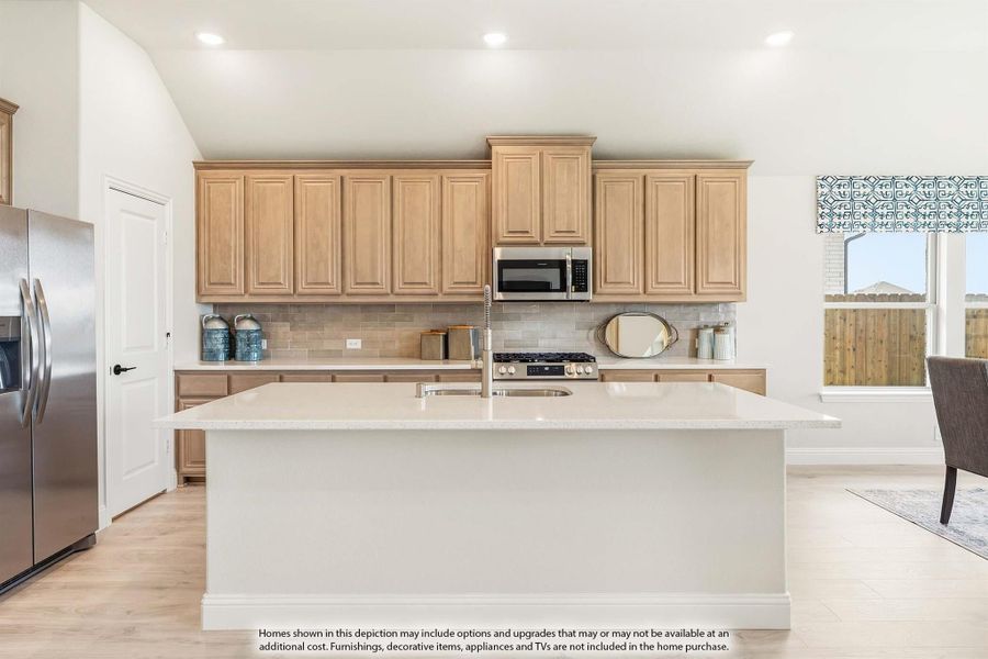 Kitchen with large white island, light wood cabinets, tile backsplash, and stainless steel appliances