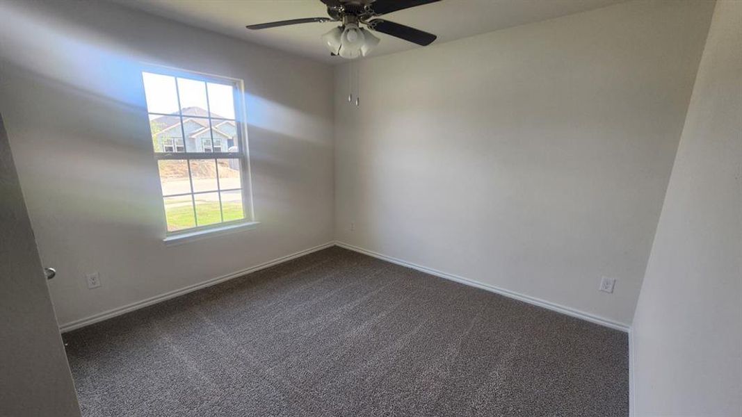 Carpeted room featuring a window with white trim, a ceiling fan, and white baseboards