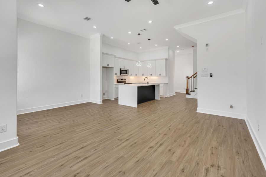 Expansive living area featuring seamless flooring throughout the first floor and tall ceilings, creating a bright and airy open-concept space.