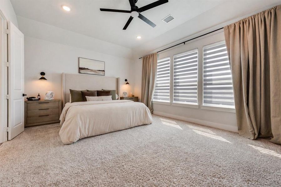 Carpeted room featuring a ceiling fan, recessed lighting, and three windows with blinds and floor-length drapes