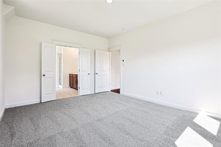 Unfurnished bedroom featuring connected bathroom and light carpet