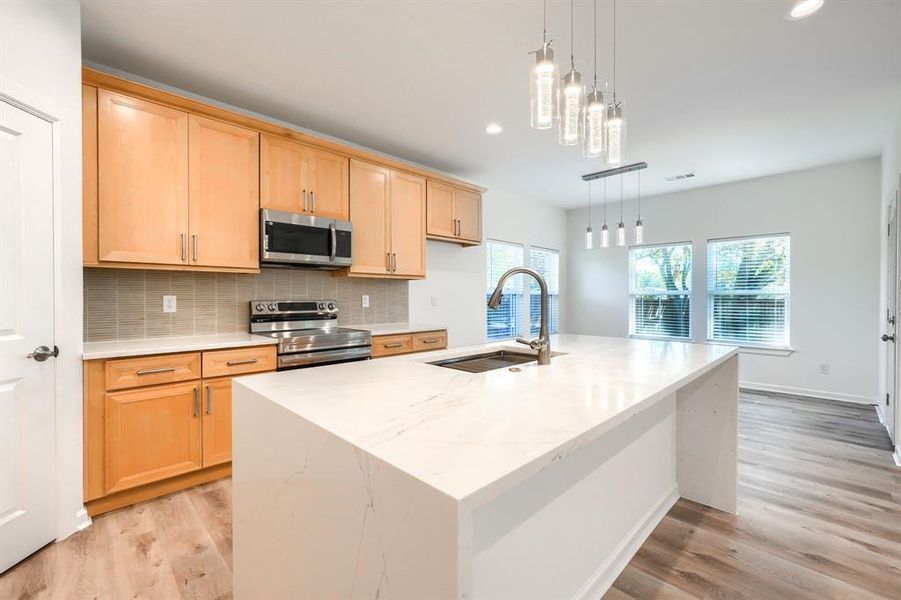 Kitchen featuring light stone countertops, decorative backsplash, pendant lighting, appliances with stainless steel finishes, and recessed lighting