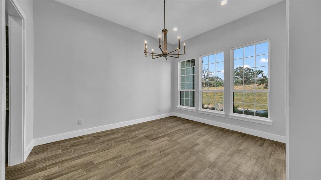 Empty room with a notable chandelier and hardwood / wood-style floors