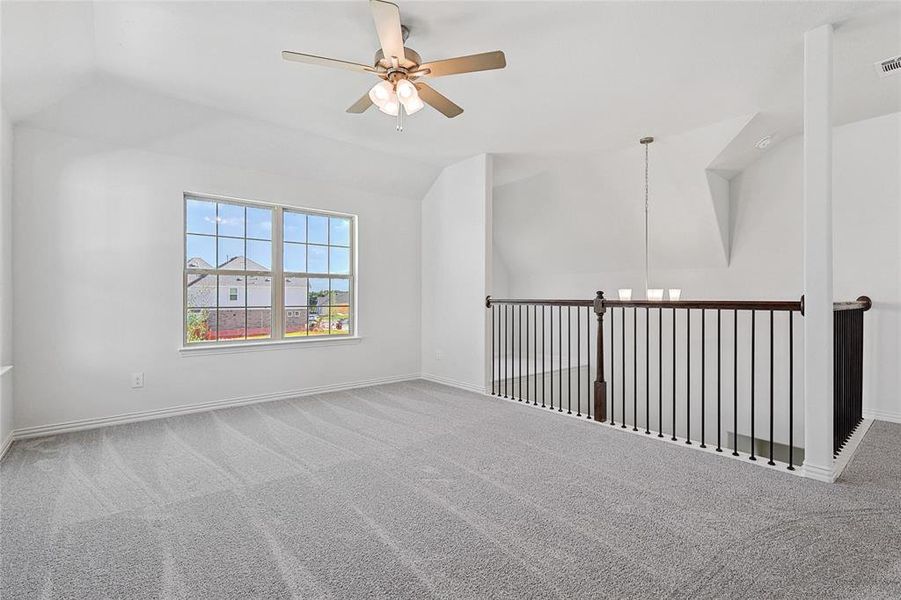 Spare room with carpet, ceiling fan, and vaulted ceiling