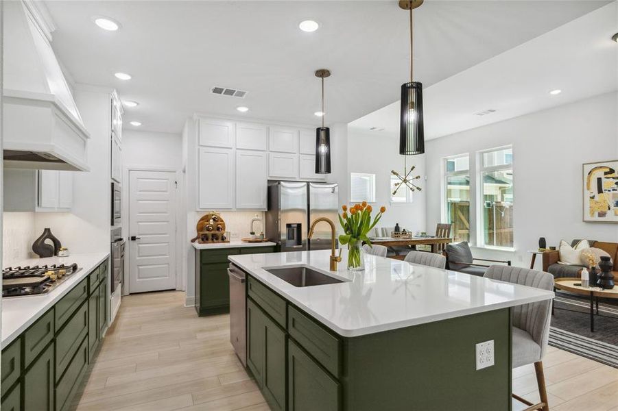 Kitchen featuring a sink, appliances with stainless steel finishes, custom range hood, green cabinetry, and visible vents Kitchen featuring a sink, appliances with stainless steel finishes, custom range hood, green cabinetry, and visible vents