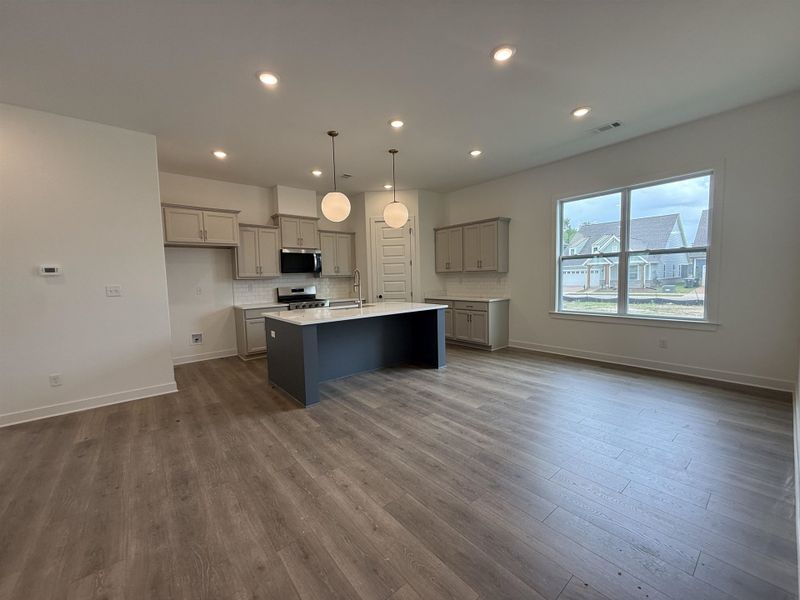 Open-concept living space featuring wood-finish flooring, recessed lighting, and a kitchen island with a light-colored countertop