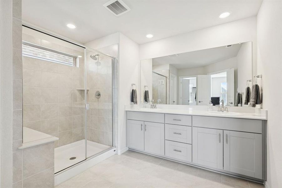 Bathroom featuring double vanity, a stall shower, light tile patterned floors, and recessed lighting