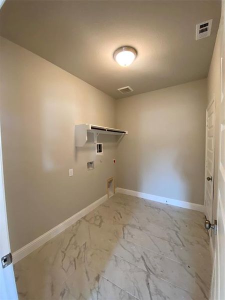 Laundry with hookup for washer & dryer, shelf, and oversized 12x24 marble-style tile floors.