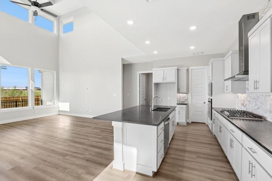 Kitchen featuring decorative backsplash, a kitchen island with sink, white cabinetry, light wood-style flooring, and recessed lighting Kitchen featuring decorative backsplash, a kitchen island with sink, white cabinetry, light wood-style flooring, and recessed lighting