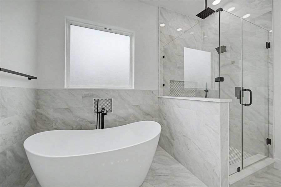Spa-inspired primary bath featuring a freestanding soaking tub, oversized glass shower, and elegant tile surroun
