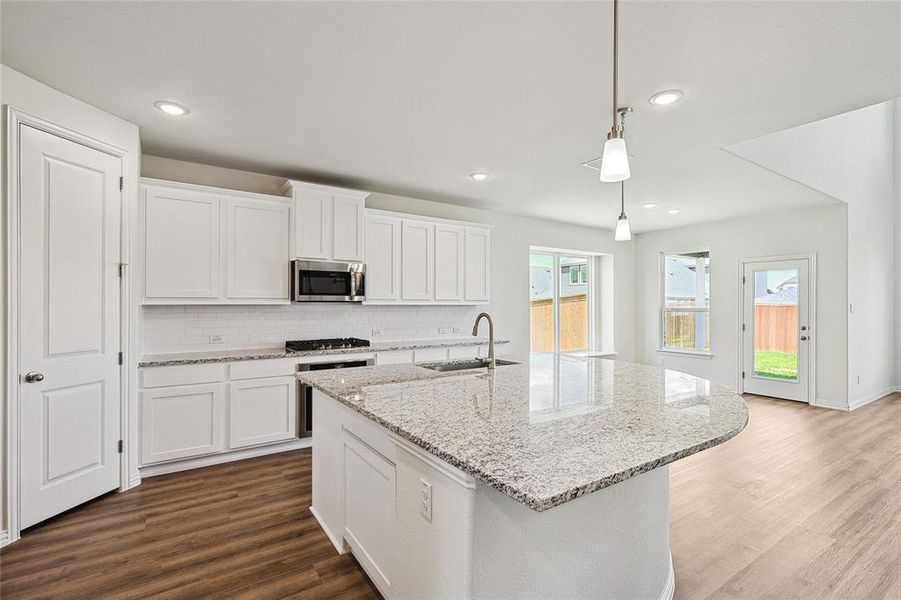 Kitchen with pendant lighting, white cabinetry, appliances with stainless steel finishes, and sink