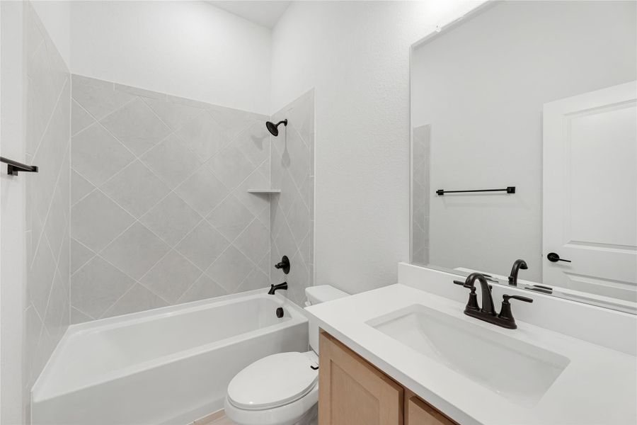 Full bathroom with tub-shower combo, diagonal tile surround, white vanity, and dark bronze fixtures Full bathroom with tub-shower combo, diagonal tile surround, white vanity, and dark bronze fixtures