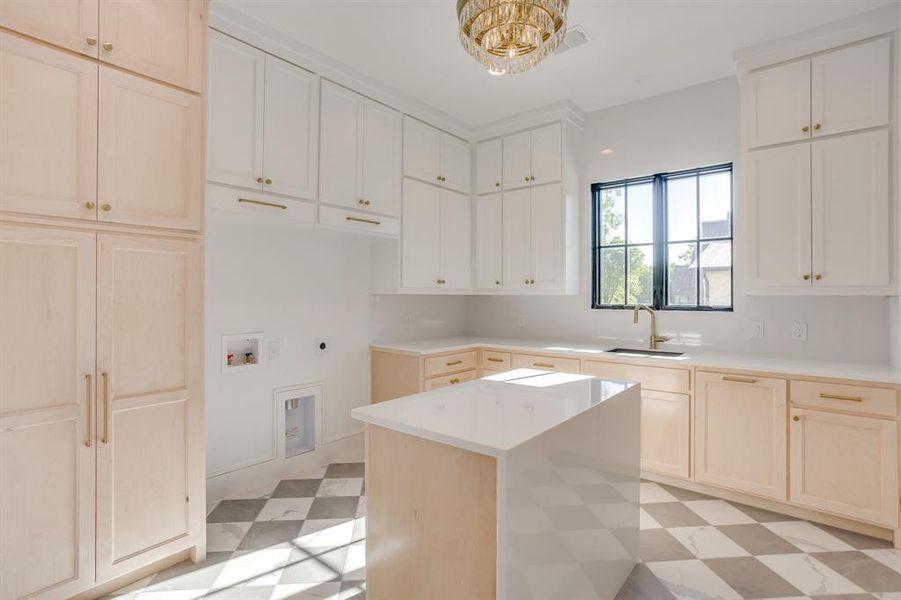 Kitchen featuring light floors, a center island, light wood finish cabinetry, and a chandelier