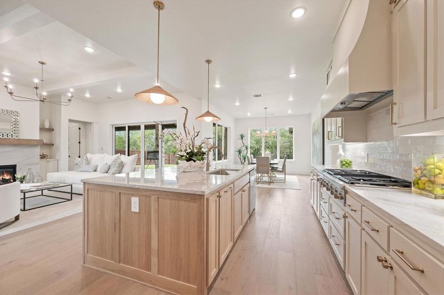 Kitchen featuring a center island with sink, sink, light hardwood / wood-style floors, a healthy amount of sunlight, and decorative backsplash