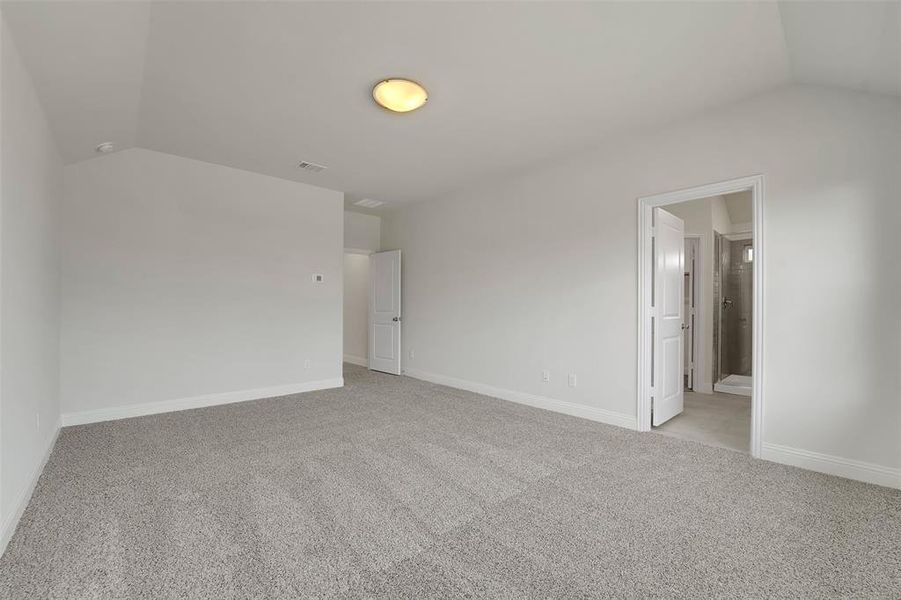 Empty room with light carpet, baseboards, visible vents, and vaulted ceiling Empty room with light carpet, baseboards, visible vents, and vaulted ceiling