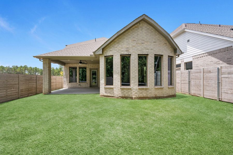 View of the back of the home showing the covered back patio and gorgeous bay windows in the primary bedroom.