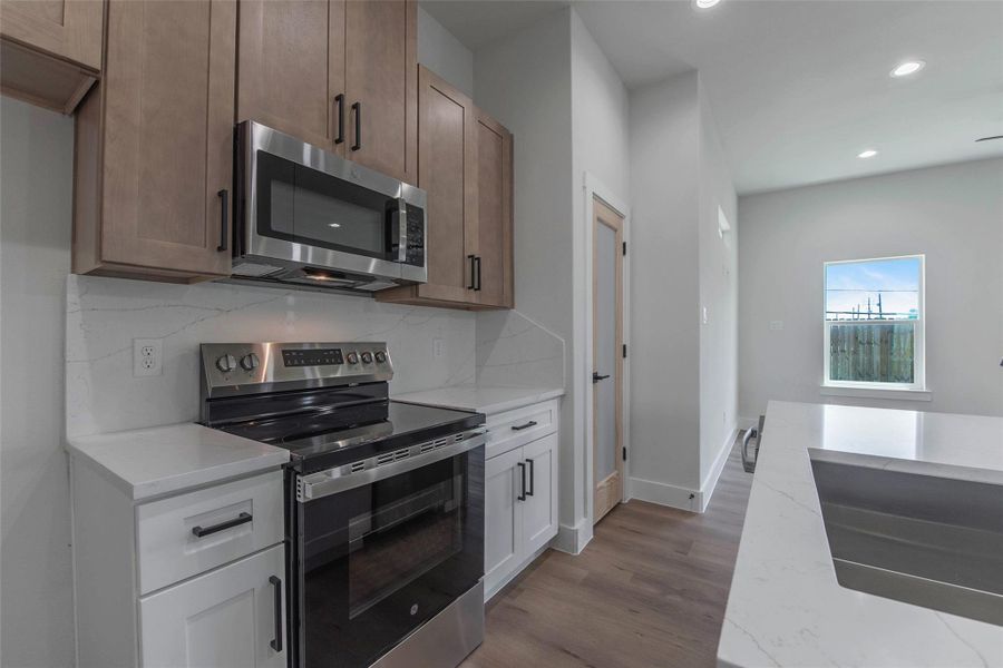 The kitchen is fully equipped with quartz countertops, a cooking range, microwave, and dishwasher, combining style and functionality for everyday living. The kitchen is fully equipped with quartz countertops, a cooking range, microwave, and dishwasher, combining style and functionality for everyday living.