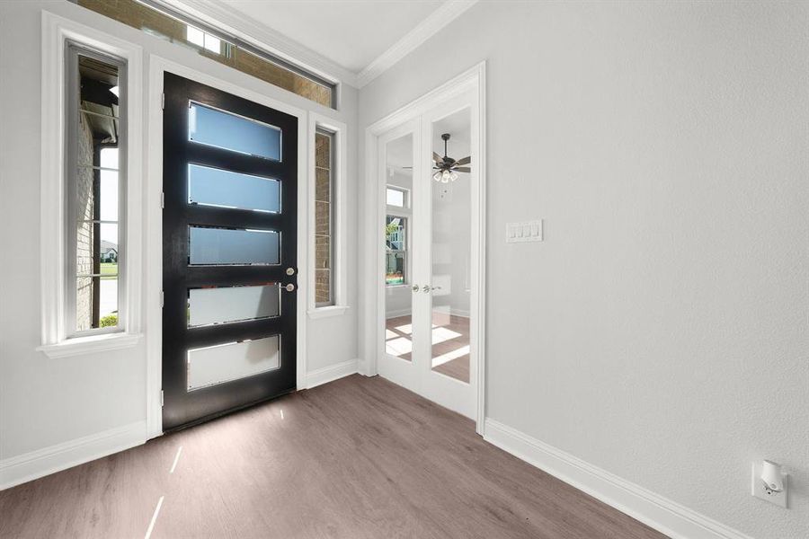 Foyer entrance with luxury vinyl floors, crown molding, plenty of natural light, with a view into the office.