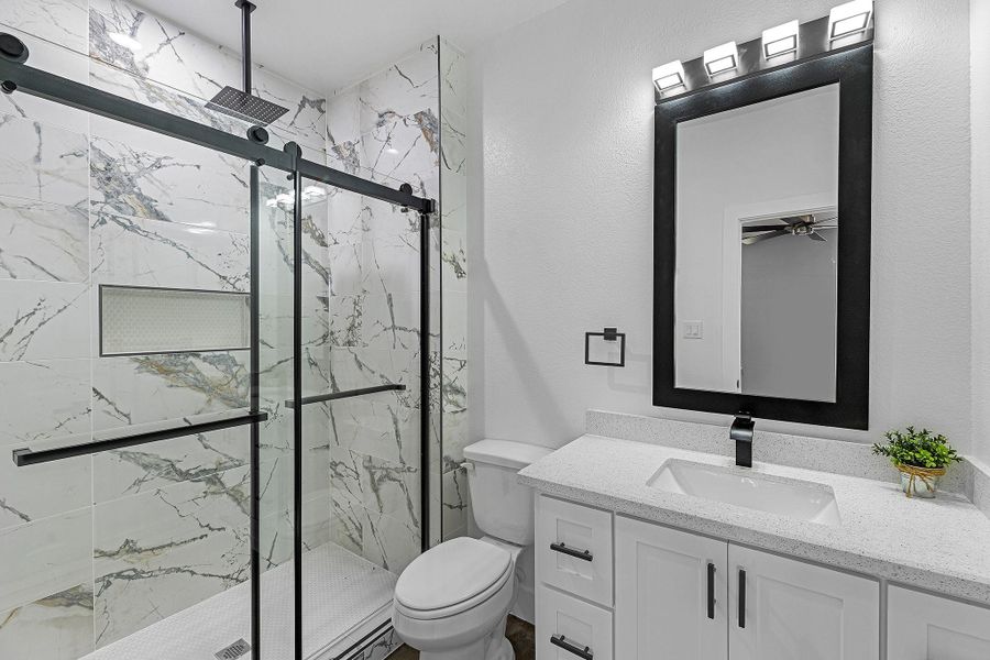 The primary bathroom offers a tile shower, granite countertops, modern fixtures and look at that shower head! A Farmhouse design.