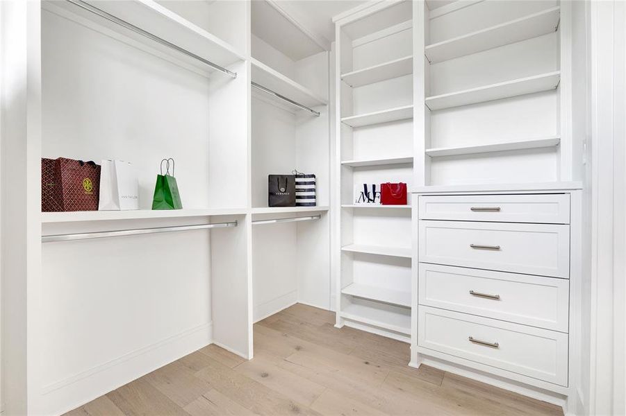 Primary walk-in closet with built in drawers shelves.