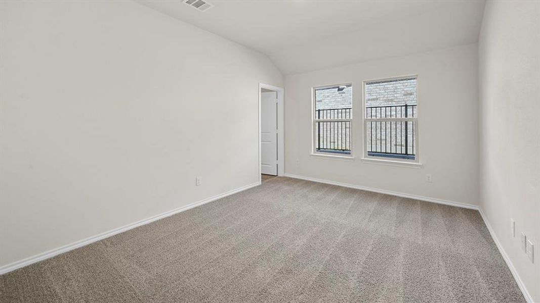 Carpeted spare room with vaulted ceiling and baseboards