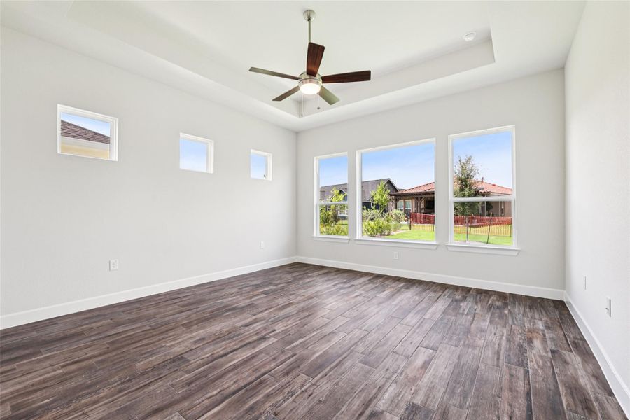 Spare room featuring dark wood-style floors, a raised ceiling, and ceiling fan