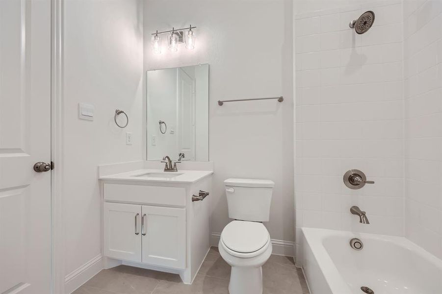 Full bathroom with vanity, toilet, tile patterned flooring, and tiled shower / bath