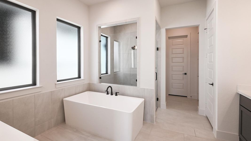 Bathroom with a freestanding bath, vanity, a stall shower, and light tile patterned flooring Bathroom with a freestanding bath, vanity, a stall shower, and light tile patterned flooring