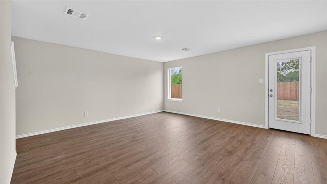 Spacious room featuring wood-finish flooring, light grey painted walls, recessed lighting, and white trim throughout