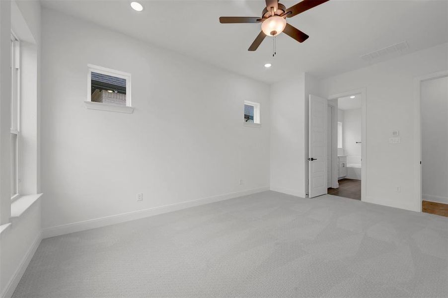 This room features light-colored carpeting, a ceiling fan with integrated lighting, and recessed ceiling lights