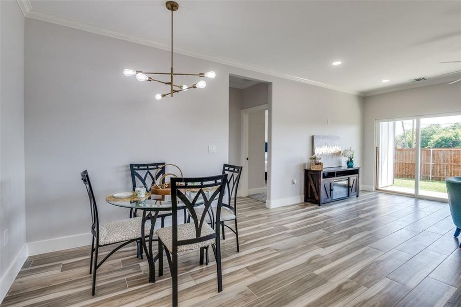 Dining room featuring light hardwood / wood-style flooring, a notable chandelier, and ornamental molding