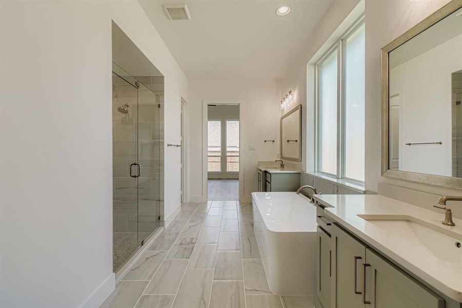 Full bath with a shower stall, two vanities, a freestanding tub, and recessed lighting Full bath with a shower stall, two vanities, a freestanding tub, and recessed lighting